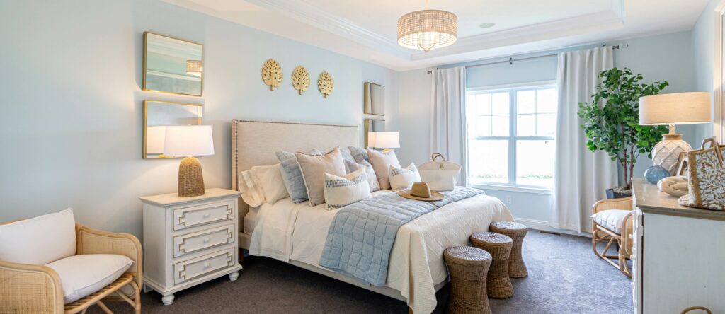 Budget-decorated Wayne Homes primary suite with natural light and layered neutral bedding